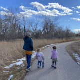 Pre-school children explore a paved trail with adults in winter