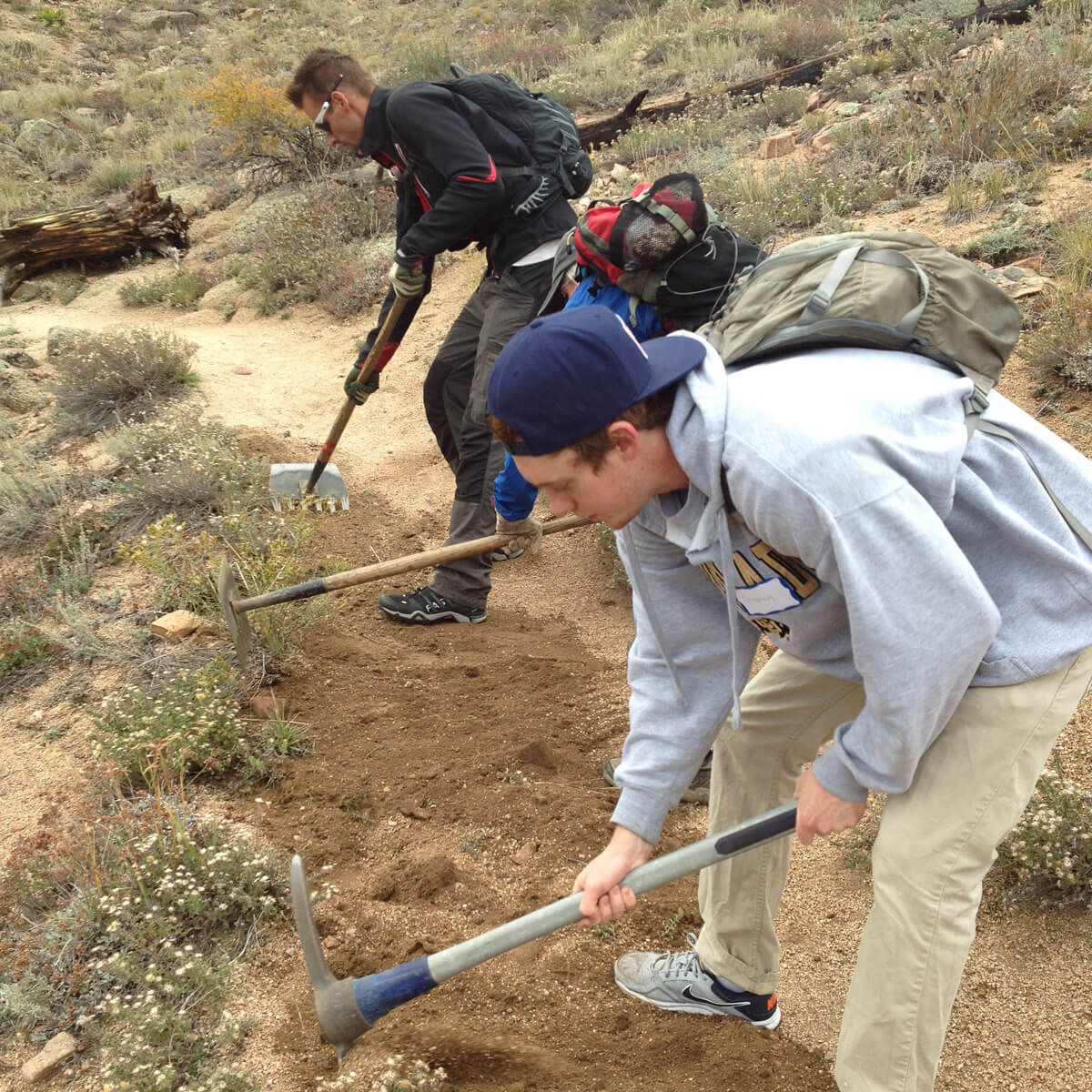 volunteers working on a trail using hand tools